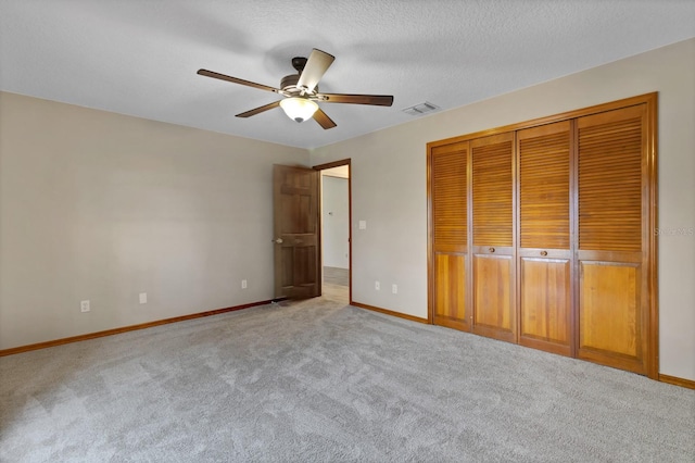 unfurnished bedroom with a textured ceiling, ceiling fan, a closet, and light carpet