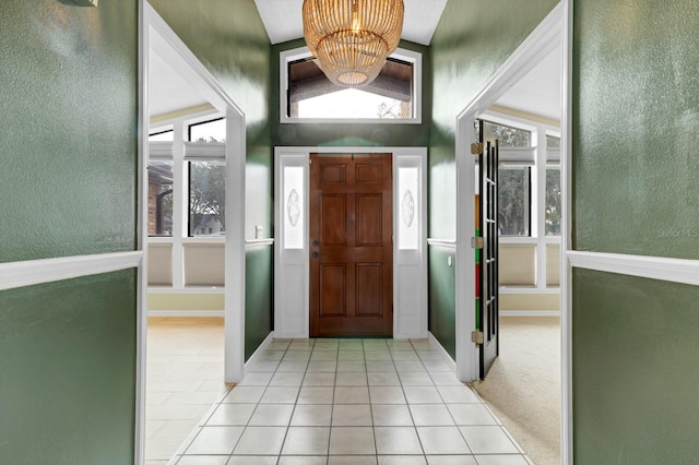 entrance foyer with vaulted ceiling, light tile patterned flooring, and a chandelier