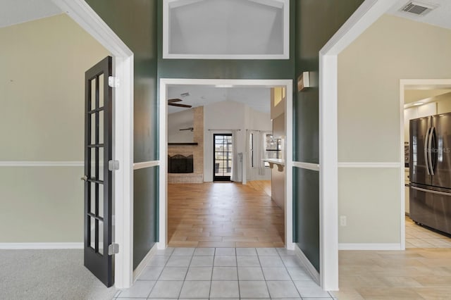 hallway with lofted ceiling and light tile patterned floors