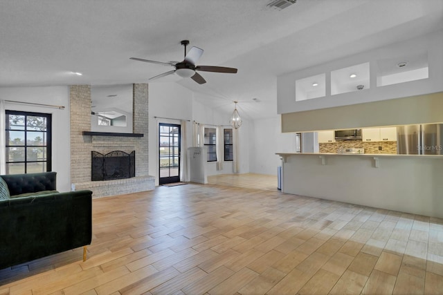 living room with vaulted ceiling, a fireplace, ceiling fan, and plenty of natural light