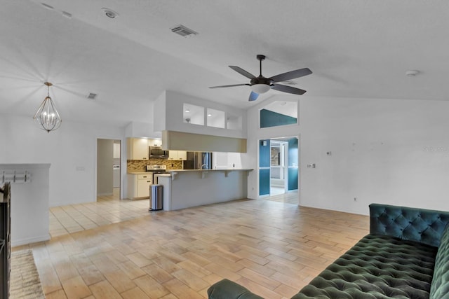 unfurnished living room featuring high vaulted ceiling and ceiling fan with notable chandelier