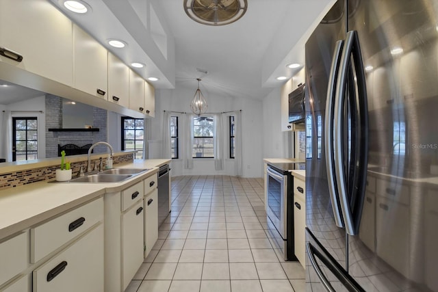 kitchen featuring sink, vaulted ceiling, backsplash, a notable chandelier, and appliances with stainless steel finishes