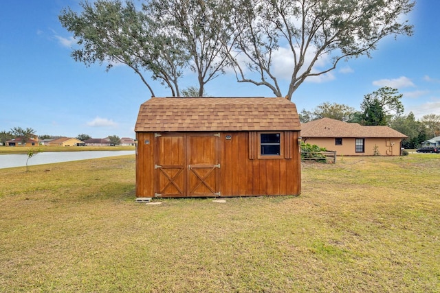 view of outdoor structure with a lawn and a water view