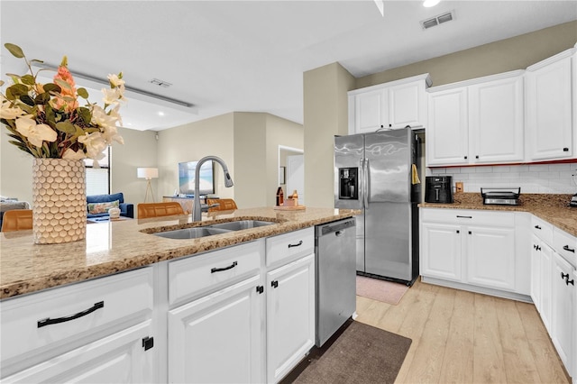 kitchen featuring sink, appliances with stainless steel finishes, white cabinetry, light stone countertops, and decorative backsplash