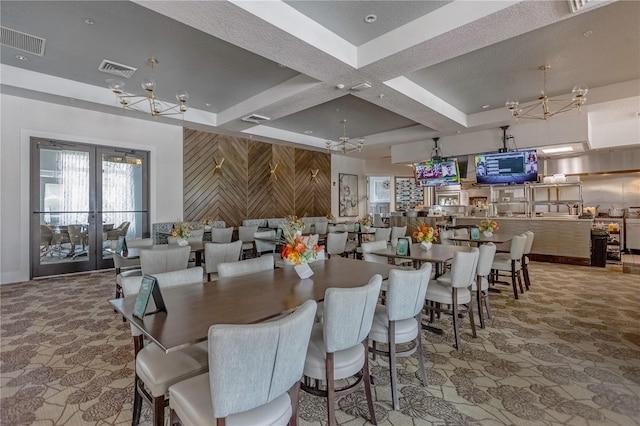 dining area featuring french doors, coffered ceiling, a chandelier, and wood walls