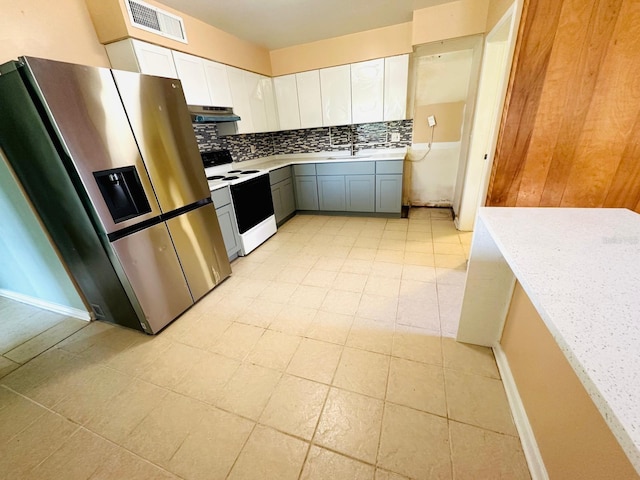 kitchen with electric range oven, stainless steel fridge, gray cabinets, white cabinets, and decorative backsplash