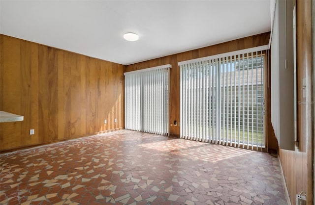 unfurnished room featuring wooden walls