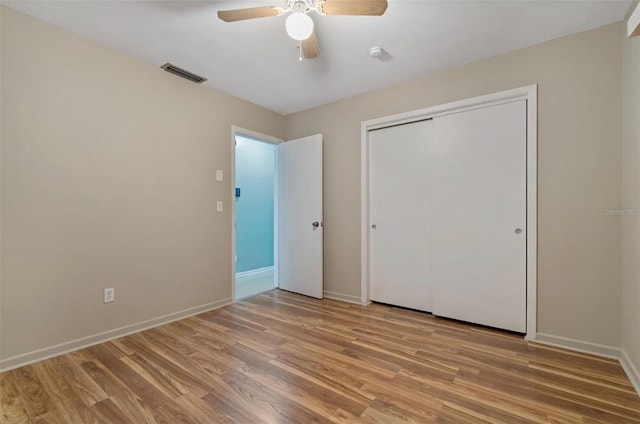 unfurnished bedroom with ceiling fan, light wood-type flooring, and a closet