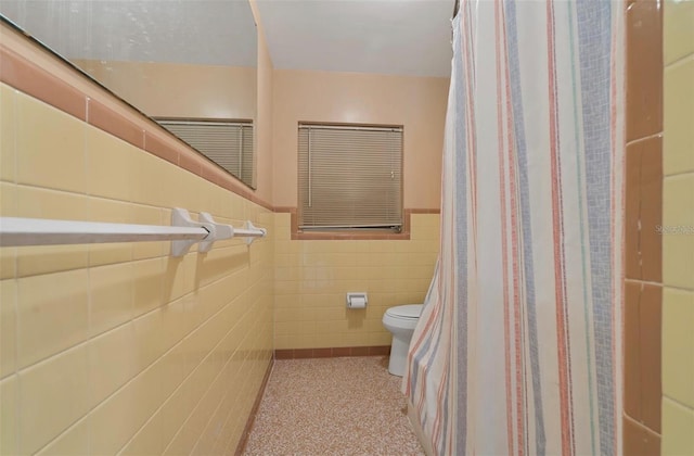 bathroom with toilet and tile walls