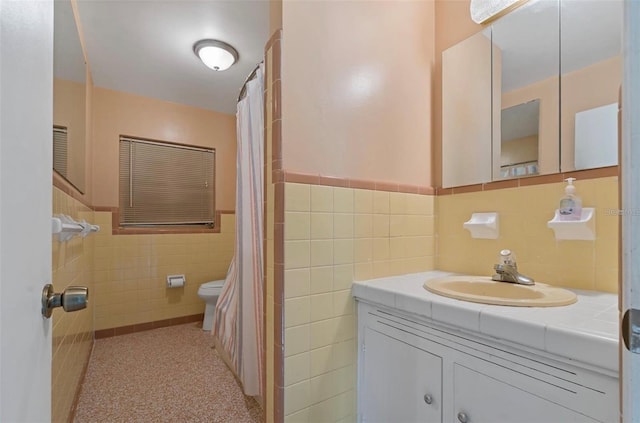 bathroom featuring toilet, tile walls, and vanity