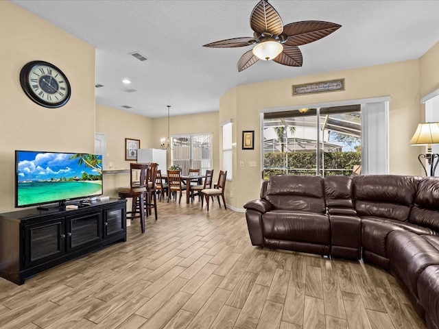 living room featuring ceiling fan with notable chandelier