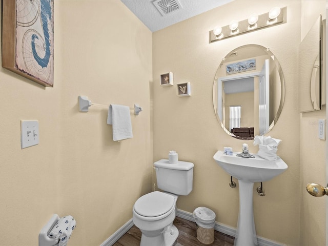 bathroom featuring a textured ceiling, wood-type flooring, and toilet