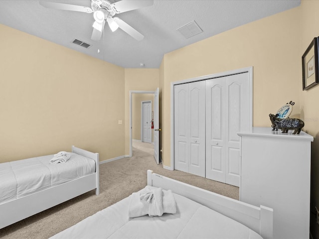 carpeted bedroom featuring a closet, ceiling fan, and a textured ceiling