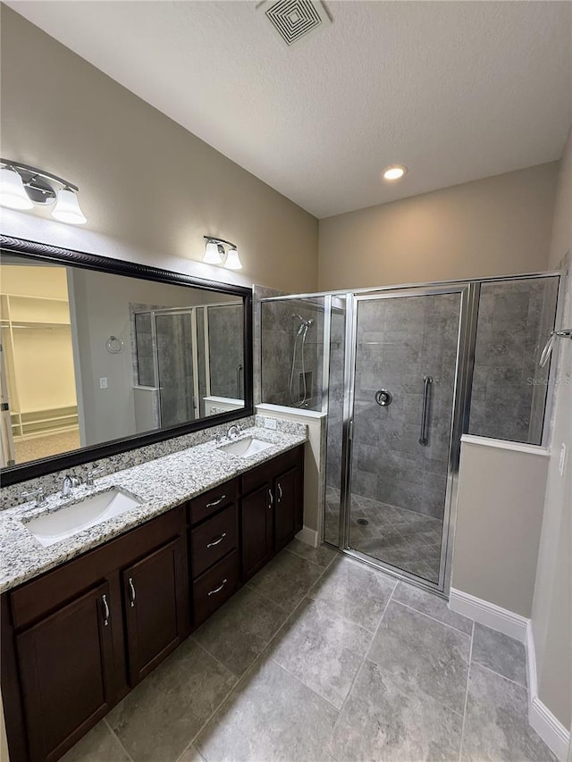 bathroom with walk in shower, vanity, and a textured ceiling