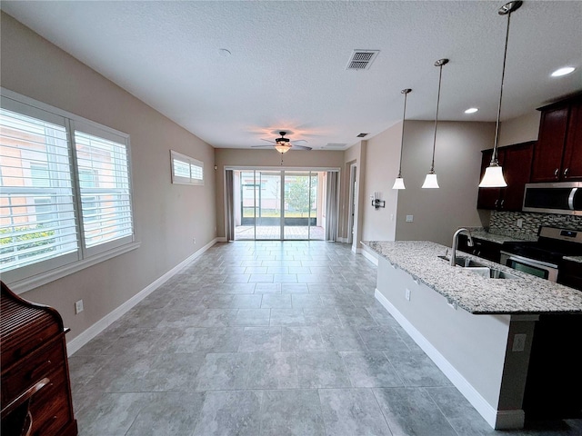 kitchen with ceiling fan, pendant lighting, sink, light stone countertops, and appliances with stainless steel finishes