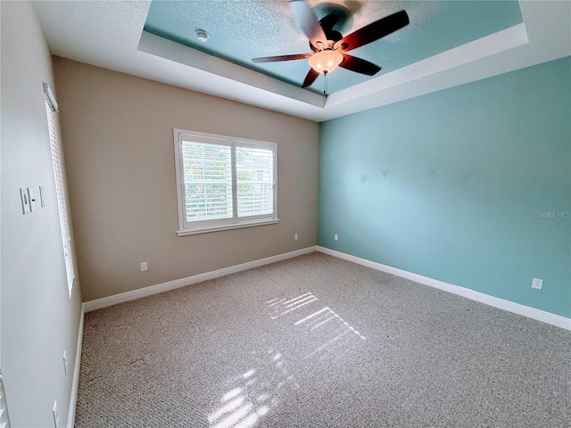 spare room with a raised ceiling, ceiling fan, a textured ceiling, and carpet flooring