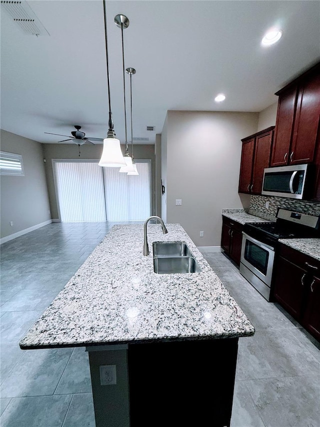 kitchen with ceiling fan, a kitchen island with sink, sink, and stainless steel appliances