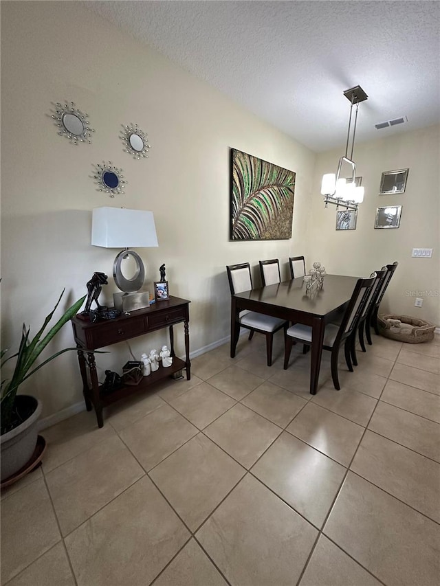 dining space featuring light tile patterned floors, a textured ceiling, and an inviting chandelier