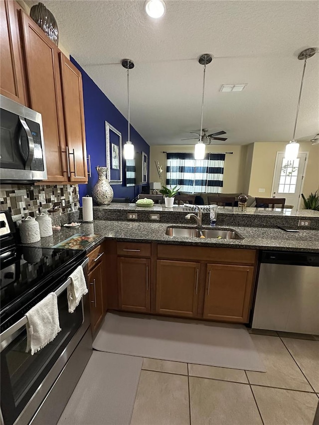 kitchen with pendant lighting, sink, light tile patterned flooring, and stainless steel appliances