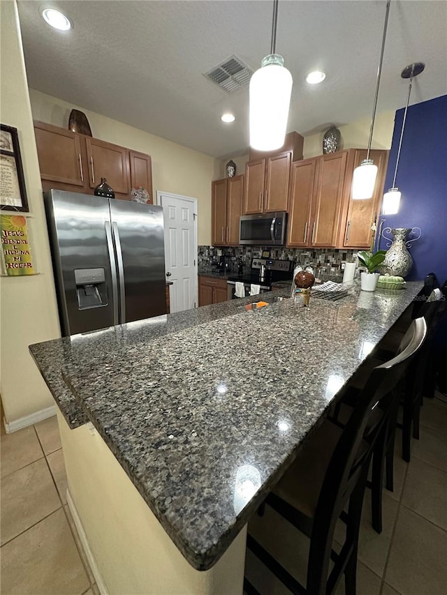 kitchen with decorative backsplash, stainless steel appliances, kitchen peninsula, and hanging light fixtures