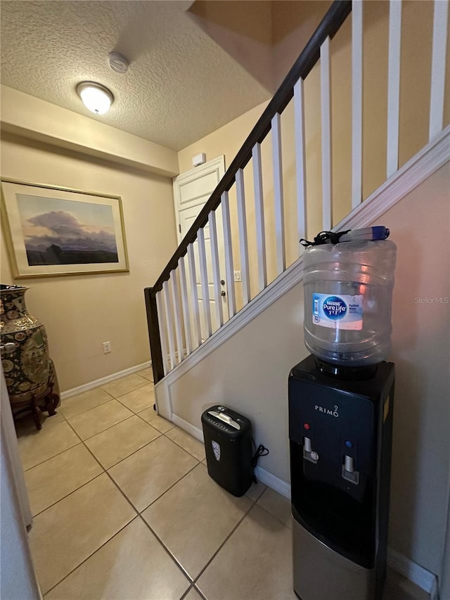 stairway with tile patterned floors and a textured ceiling