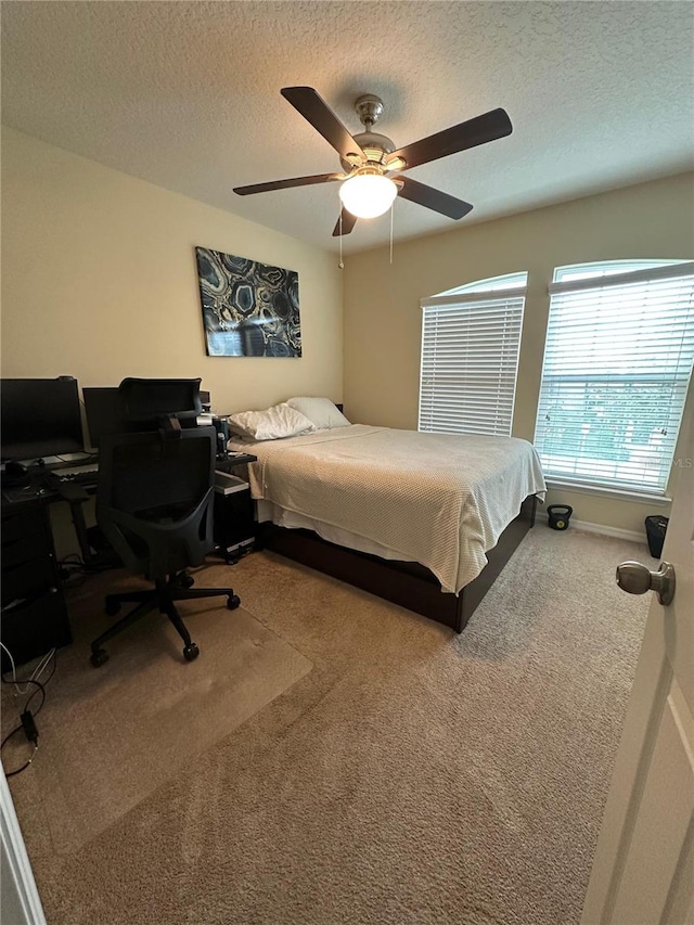 bedroom with ceiling fan, carpet, and a textured ceiling