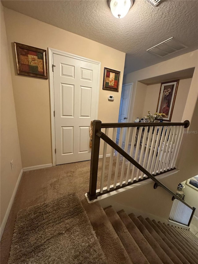 stairs featuring carpet floors and a textured ceiling