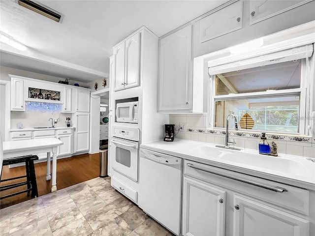 kitchen with white cabinetry, sink, white appliances, and decorative backsplash