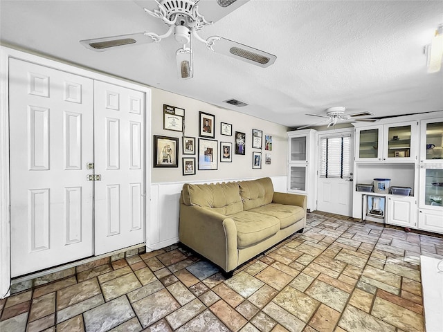 living room with a textured ceiling and ceiling fan