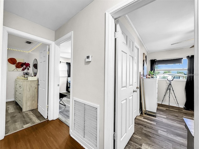 corridor with dark wood-type flooring and crown molding