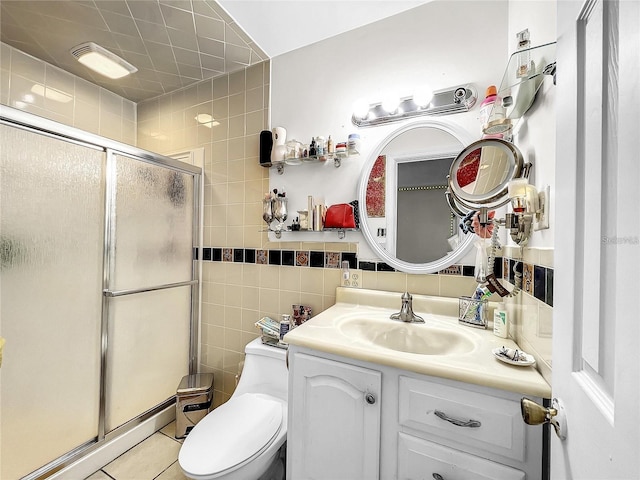 bathroom with tile patterned floors, toilet, a shower with shower door, tile walls, and vanity