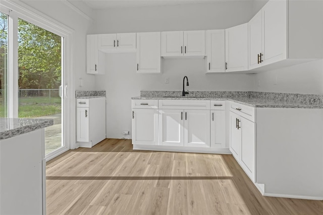 kitchen featuring white cabinets, light stone counters, and sink