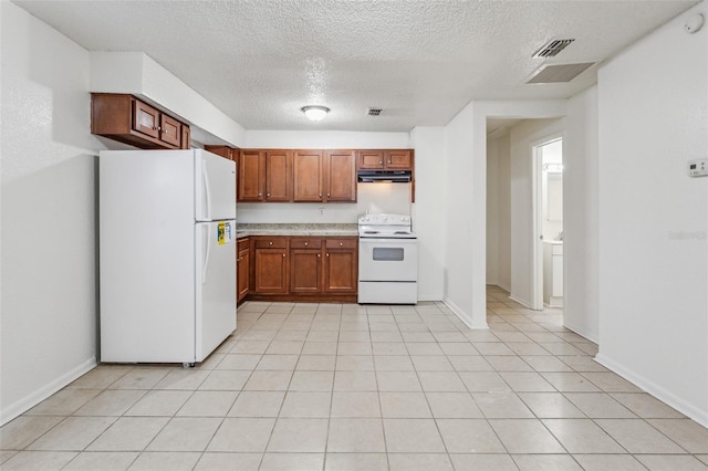 kitchen with light tile patterned flooring, white appliances, and a textured ceiling