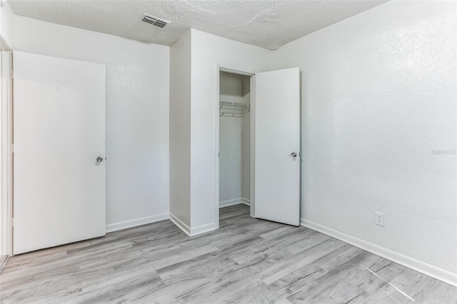 unfurnished bedroom with light hardwood / wood-style floors, a textured ceiling, and a closet