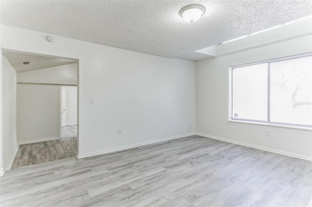 spare room featuring light hardwood / wood-style floors and a textured ceiling