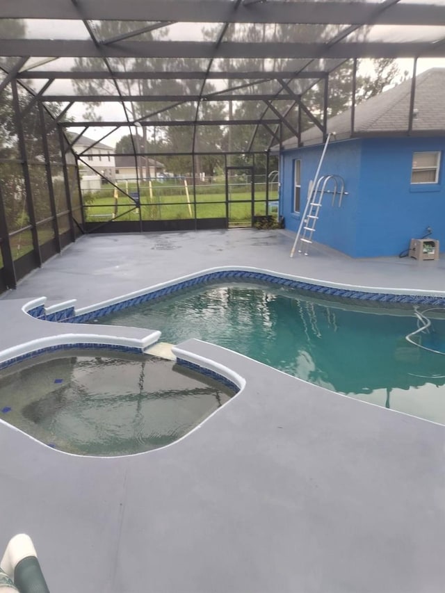 view of pool with glass enclosure, an in ground hot tub, and a patio