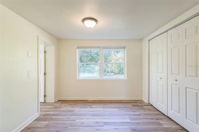 unfurnished bedroom featuring light hardwood / wood-style floors and a closet