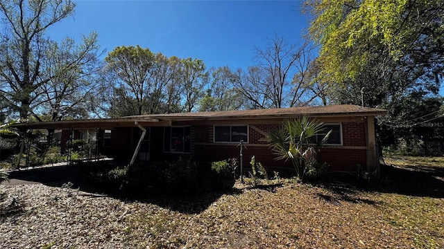 ranch-style house featuring brick siding and a carport