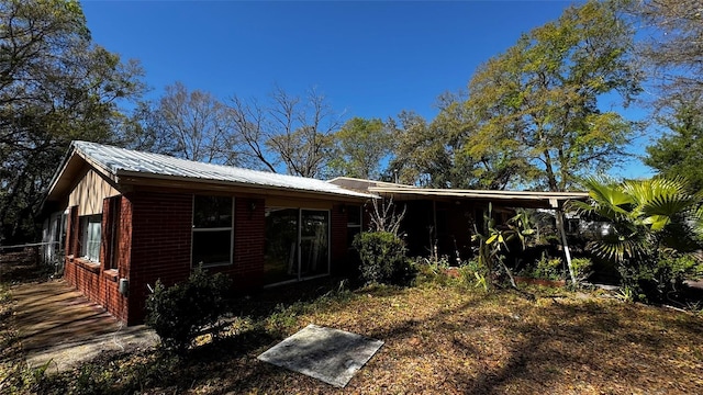 exterior space featuring metal roof and brick siding