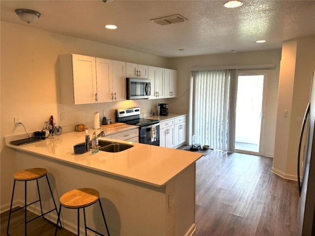 kitchen featuring stainless steel appliances, white cabinetry, sink, and kitchen peninsula