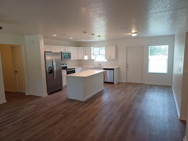 kitchen featuring pendant lighting, sink, a kitchen island, white cabinetry, and stainless steel appliances