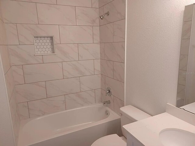 full bathroom featuring vanity, tiled shower / bath combo, and toilet