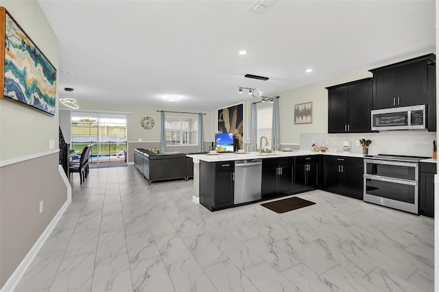 kitchen featuring stainless steel appliances, kitchen peninsula, tasteful backsplash, and sink