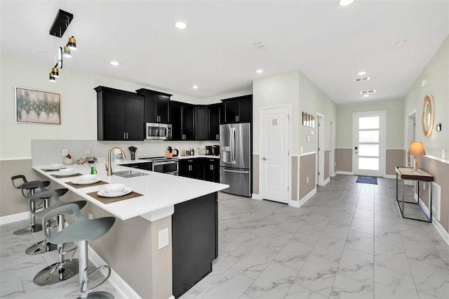 kitchen with kitchen peninsula, a breakfast bar area, stainless steel appliances, decorative backsplash, and sink