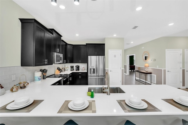 kitchen with kitchen peninsula, backsplash, sink, and stainless steel appliances