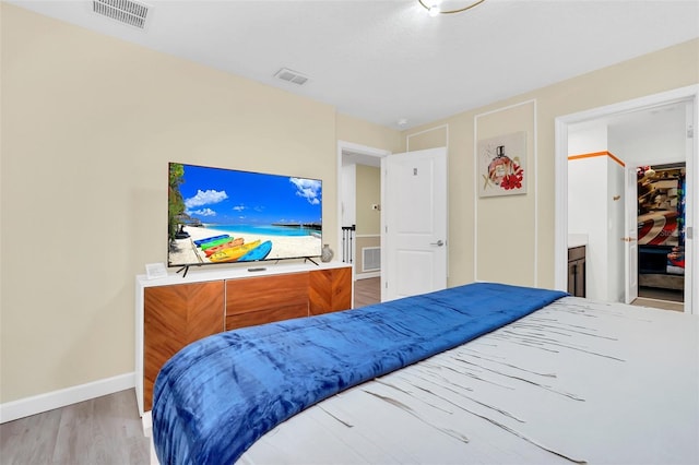 bedroom with ensuite bathroom and light hardwood / wood-style floors