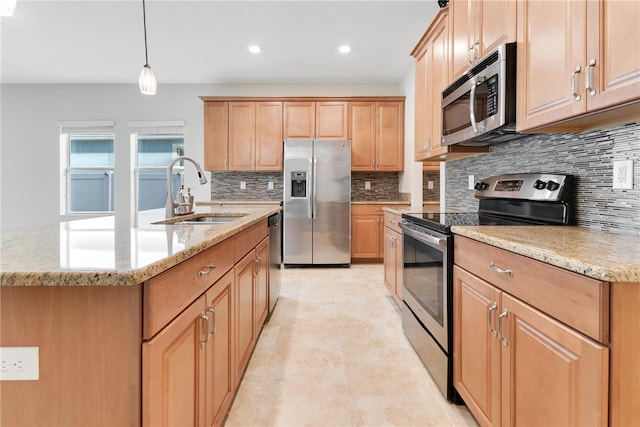 kitchen featuring sink, stainless steel appliances, light stone counters, an island with sink, and pendant lighting