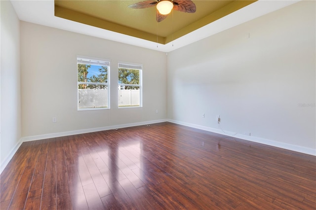 spare room with ceiling fan, dark hardwood / wood-style flooring, and a raised ceiling