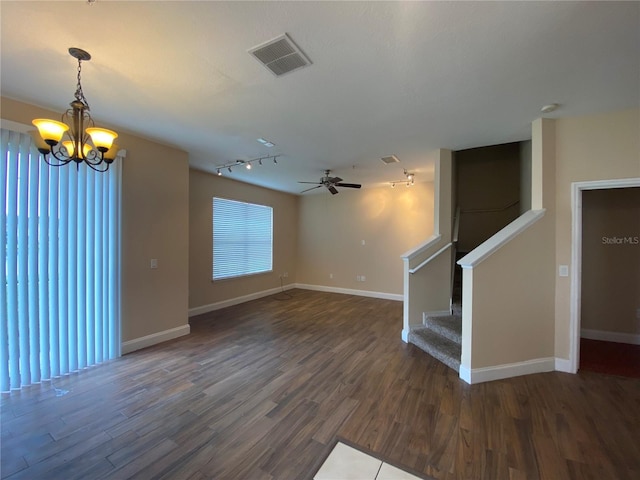 unfurnished living room with dark wood-type flooring, ceiling fan with notable chandelier, and rail lighting