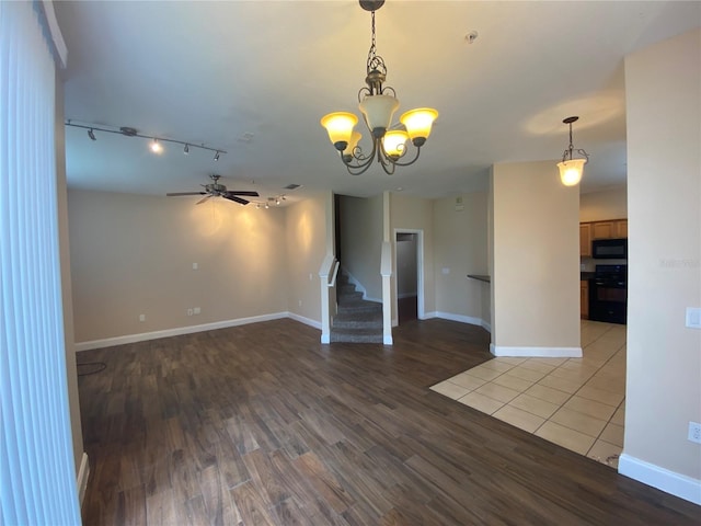 empty room featuring track lighting, ceiling fan with notable chandelier, and hardwood / wood-style flooring